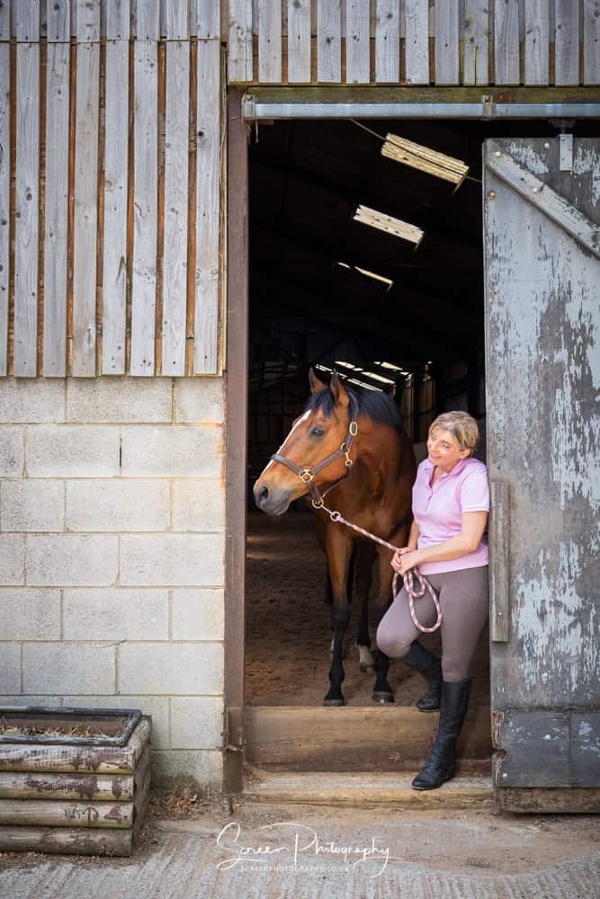 Equine portrait photography nottingham female lady looking out of barn door with her horse
